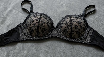 Elegant black lace bra resting on a soft, textured gray background creating a sophisticated and