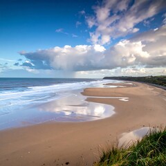 A coastal landscape features a wide, sandy beach merging into the ocean under a cloudy sky. The horizon is filled with white caps