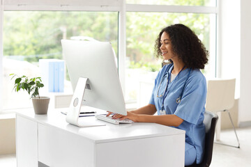 Female African-American medical student using computer at table in office