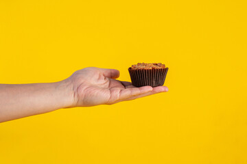 Toffee cake, a close up of homemade caramel nut chocolate cake bakery and hand isolated on yellow...