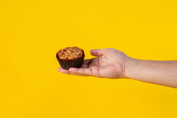 Toffee cake, a close up of homemade caramel nut chocolate cake bakery and hand isolated on yellow background.