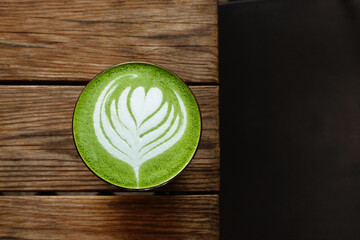A cup of green tea matcha latte on wooden background           