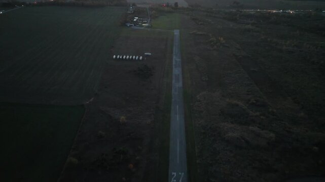 A high-angle aerial shot moves forward from one end of the abandoned Markham Airport runway to the other, capturing the full length of the deserted tarmac at dusk