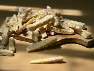 Raw tempeh slices in stick form on a wooden cutting board. Preparing to cook tempeh. Preparing to eat tempeh.