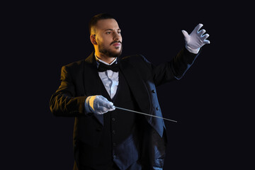 Young male conductor on black background