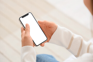 Young woman using blank mobile phone in bedroom, closeup