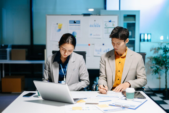 business team working late at night, discussing documents and analyzing data in a modern office. overtime, planning, and productivity.