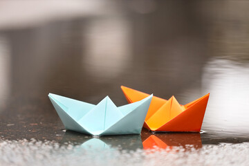 Obraz premium Origami boats floating on shallow water puddle outdoors, closeup