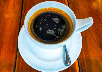 Glass cup of americano black coffee with spoon and plate.