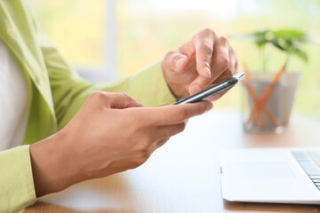 Fototapeta premium Young woman using mobile phone to search online at home, closeup