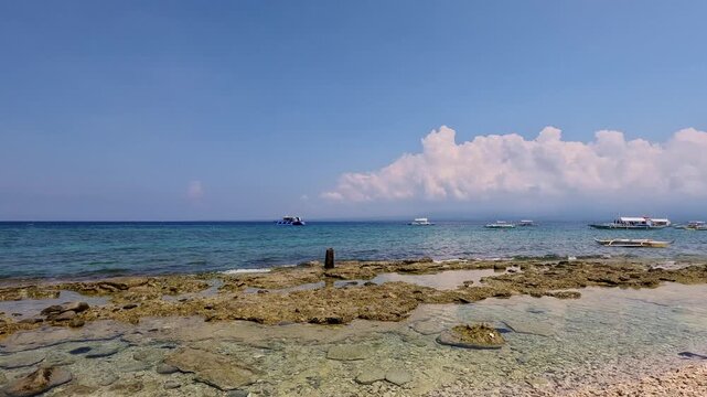 Pan right to the vast expanse of idyllic coastline during the low tide in Apo Island, a popular summer travel destination in Dauin, Philippines