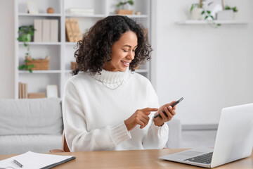 Young African-American woman using mobile phone to search online at home
