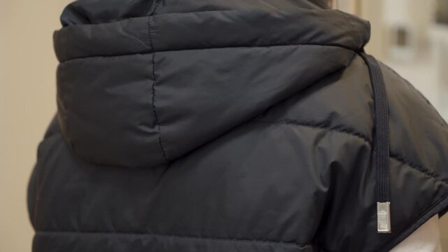 The drawstring on a fabric puffer jacket hood is pulled tight. This action creates a soft, sliding rustle.