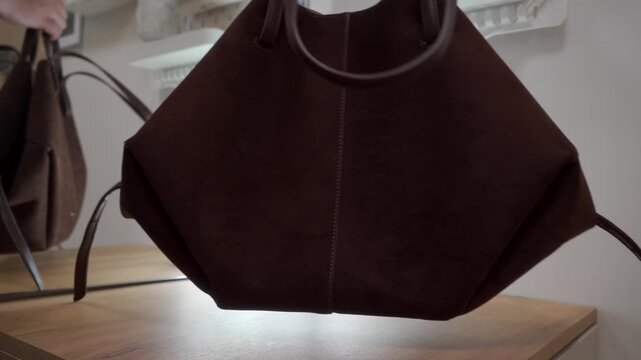 A suede handbag is set down on a wooden surface. This action creates a soft, gentle thud.
