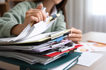 Young woman searching through files at desk in office, closeup