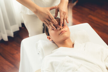 Caucasian woman enjoying relaxing anti-stress head massage and pampering facial beauty skin recreation leisure in dayspa modern light ambient at luxury resort or hotel spa salon. Quiescent