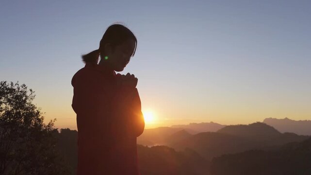Girl praying to god on mountain sunset background	