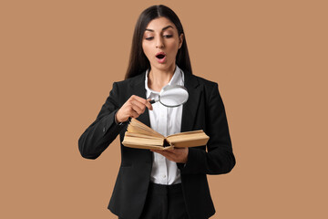 Shocked businesswoman with magnifier and book on beige background. Search concept