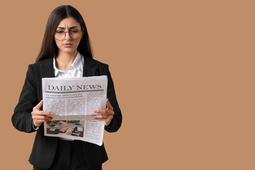 Young businesswoman reading newspaper on beige background. Search concept