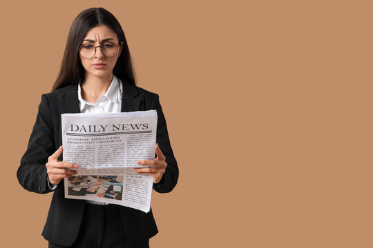 Young businesswoman reading newspaper on beige background. Search concept