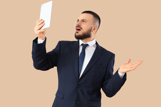 Shocked businessman using tablet computer on beige background. Search concept