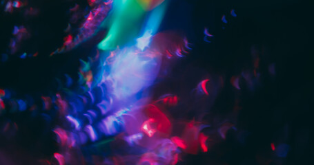 Holographic flare blur. Light lens. Red purple green neon colorful luminosity on dark black background. Cosmic spectrum abstract optical effect.