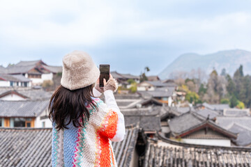 Young female tourist taking pictures at Lijiang Ancient Town, the famous tourist destination in Yunnan Province, China