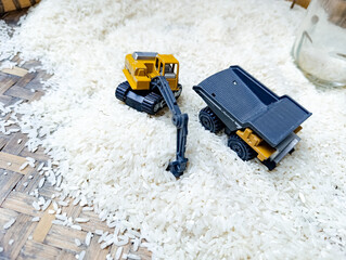 Toy Excavator and Dump Truck on White Rice Surface Playful Miniature Scene