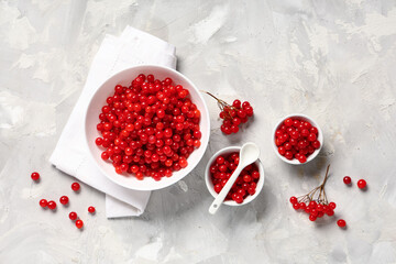 Bowls with fresh viburnum berries on grey background