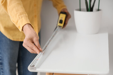 Mature woman measuring table at home, closeup