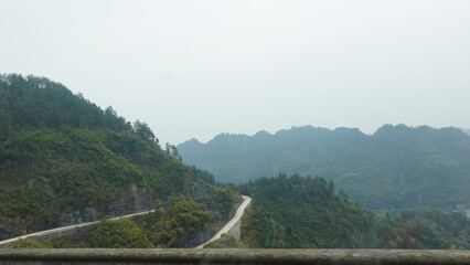 A winding road through a mountainous region, The location offers stunning panoramic views of the surrounding mountains in Hunan China