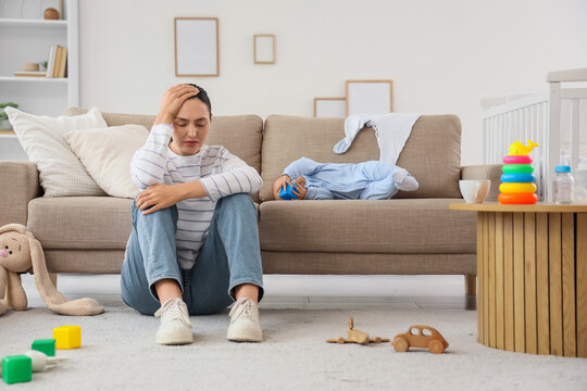 Young mother suffering from postnatal depression and her baby on sofa at home
