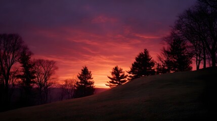 A dramatic crimson and purple sunset paints the sky above a silhouetted hillside with scattered trees