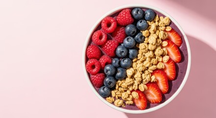Colorful mixed berry smoothie bowl with granola and fresh fruit on pink background