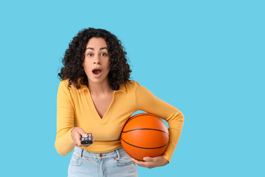 Shocked female African-American sports fan watching basketball on blue background