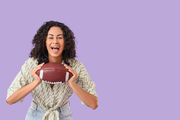 Female African-American sports fan with rugby ball on lilac background