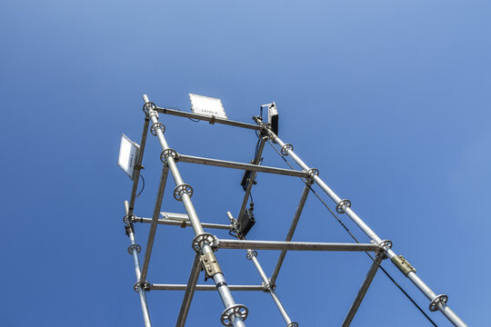 Looking up at metal tower and communication antenna against clear blue sky. modern industrial construction and technology framework symbolizing connection and progress