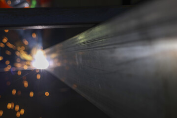 Close up of an industrial welding process creating bright hot spark. powerful metalwork job with focused precision, showing fabrication of steel beam in dark factory