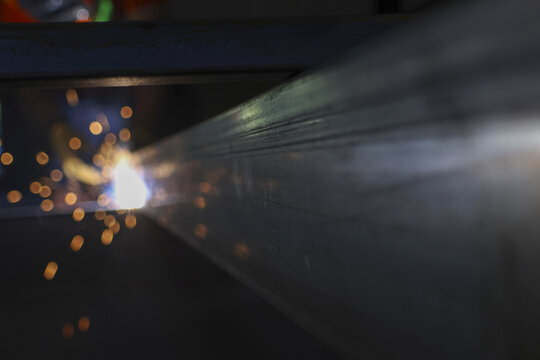 Close up view of powerful industrial welding process. Bright light and hot sparks flying from molten metal during steel fabrication. focused scene of manufacturing and construction work