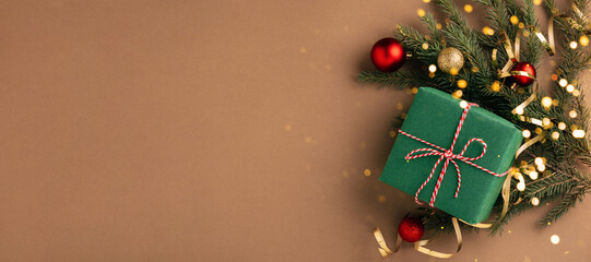 Christmas gift, fluffy fir branches, golden sparkling streamers and Christmas tree decorations, beige background