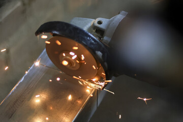 Industrial grinder tool cutting steel metal in workshop. Many hot bright sparks flying from action. powerful process for manufacturing, craft, and fabrication work