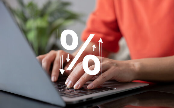 Closeup of hands typing on a laptop keyboard, with a prominent graphic overlay of a percentage sign and upward arrows, representing financial growth, online trading, or digital commerce concepts