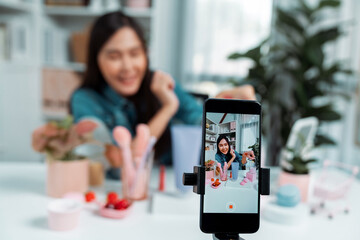 Selective focus phone with young beautiful Asian showing cosmetic makeup lipstick matte pastel color testing bestseller collection on arm test promotion on social media online recording. Stratagem.