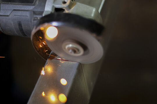 Industrial grinder tool creates hot sparks of light during metal grinding in workshop. This powerful process shows intense friction and heat from spinning disc