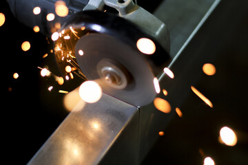 Powerful industrial angle grinder cutting metal sheet creates shower of bright hot sparks. intense process of metalworking and fabrication in workshop