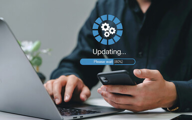A person updating software on a laptop and smartphone, with a progress bar and loading icon, representing technology, digital transformation, and system maintenance