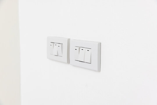 Triple lighting switch on white concrete wall
