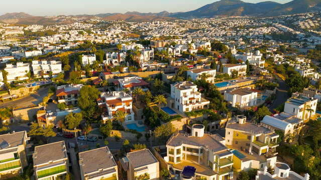 Bodrum, Turkey. Aerial view of luxurious white villas terraced on slopes with courtyards and blue-water swimming pools.. Aerial View - Powered by Adobe