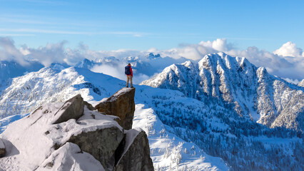 Hiker Standing On Snowy Mountain Peak Overlooking Vast Snowy Range In BC Canada