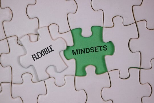 white puzzle with a green center piece labeled Mindsets and a white piece labeled Flexible, symbolizing adaptability, positive thinking, and collaborative problem solving in teams and personal growth.